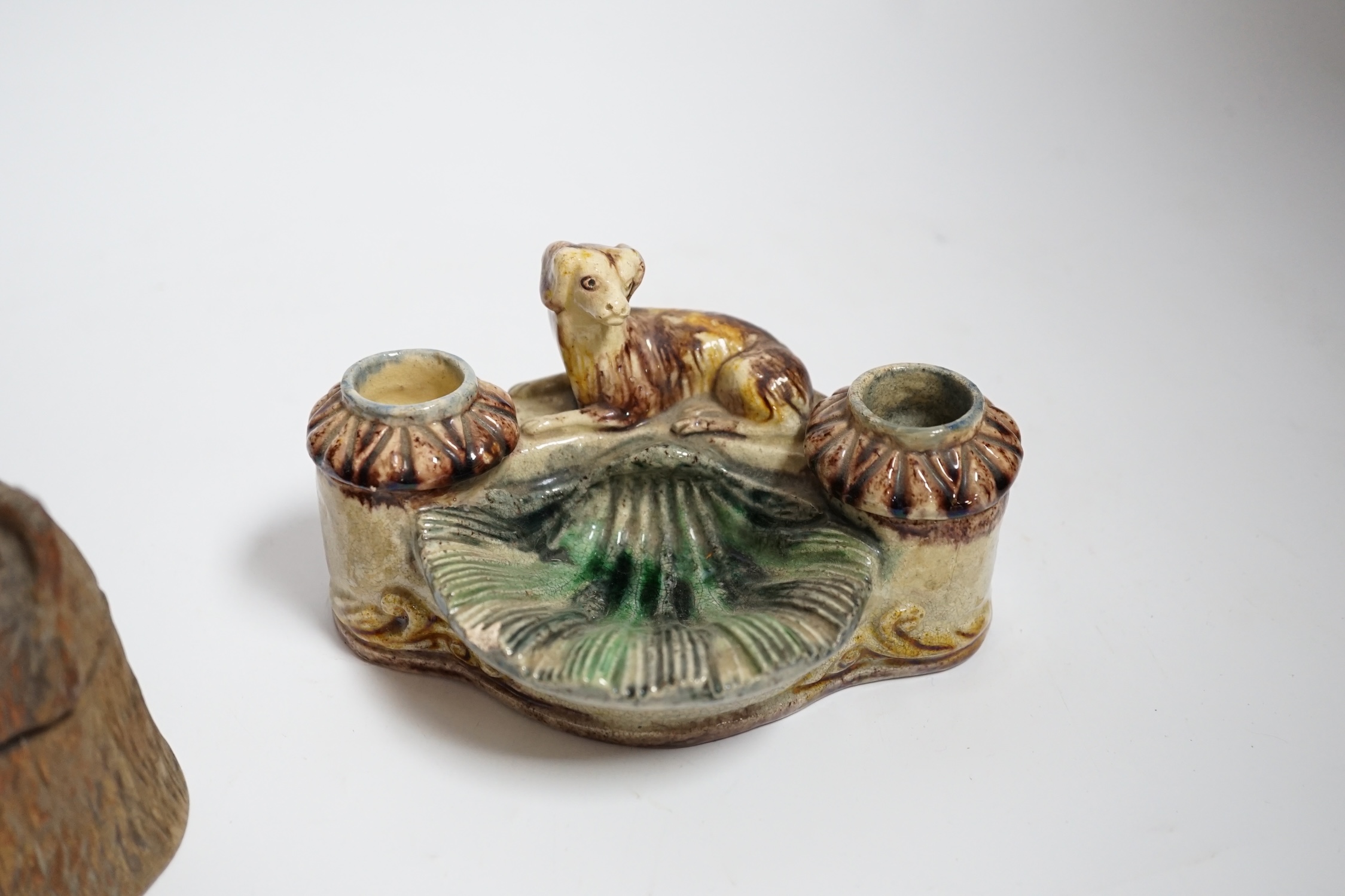 A Black Forest carved bear inkwell and a majolica inkwell surmounted with a dog, largest 14cm wide
